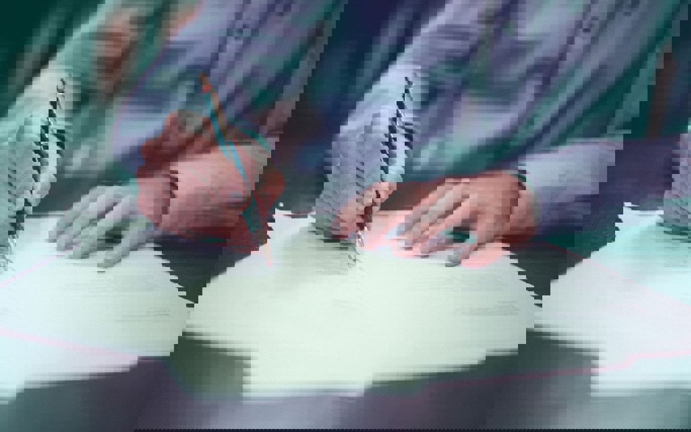 Person underskriver dokument med en kuglepen.