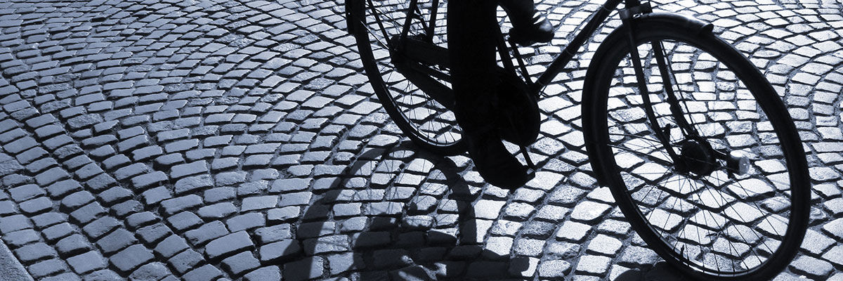 Nederste del af en cykel, der cykler på brosten.