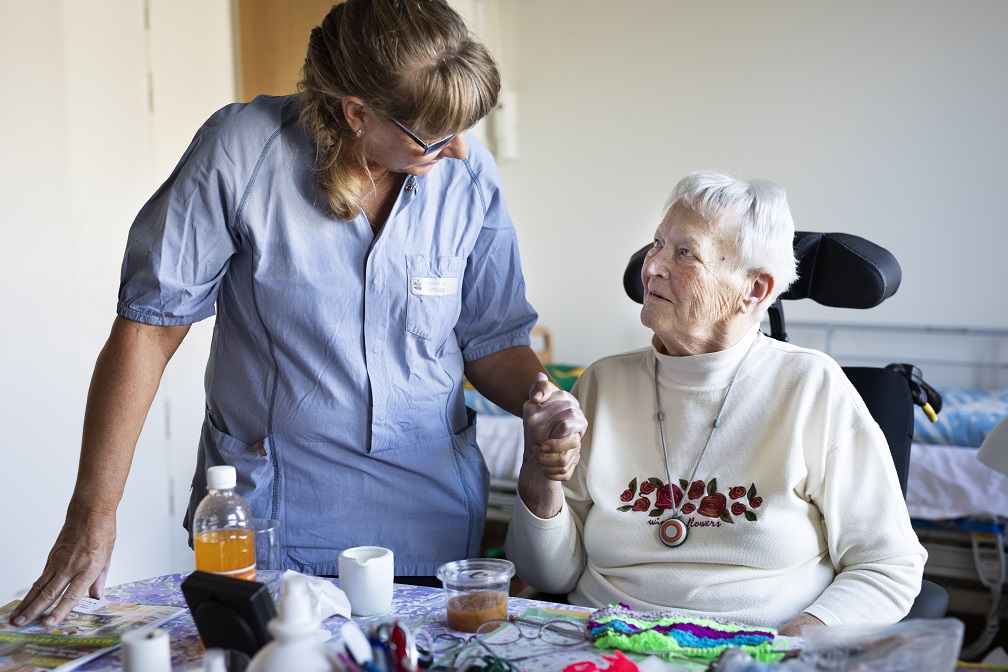 SOSU-hjælper holder ældre dame i hånden.