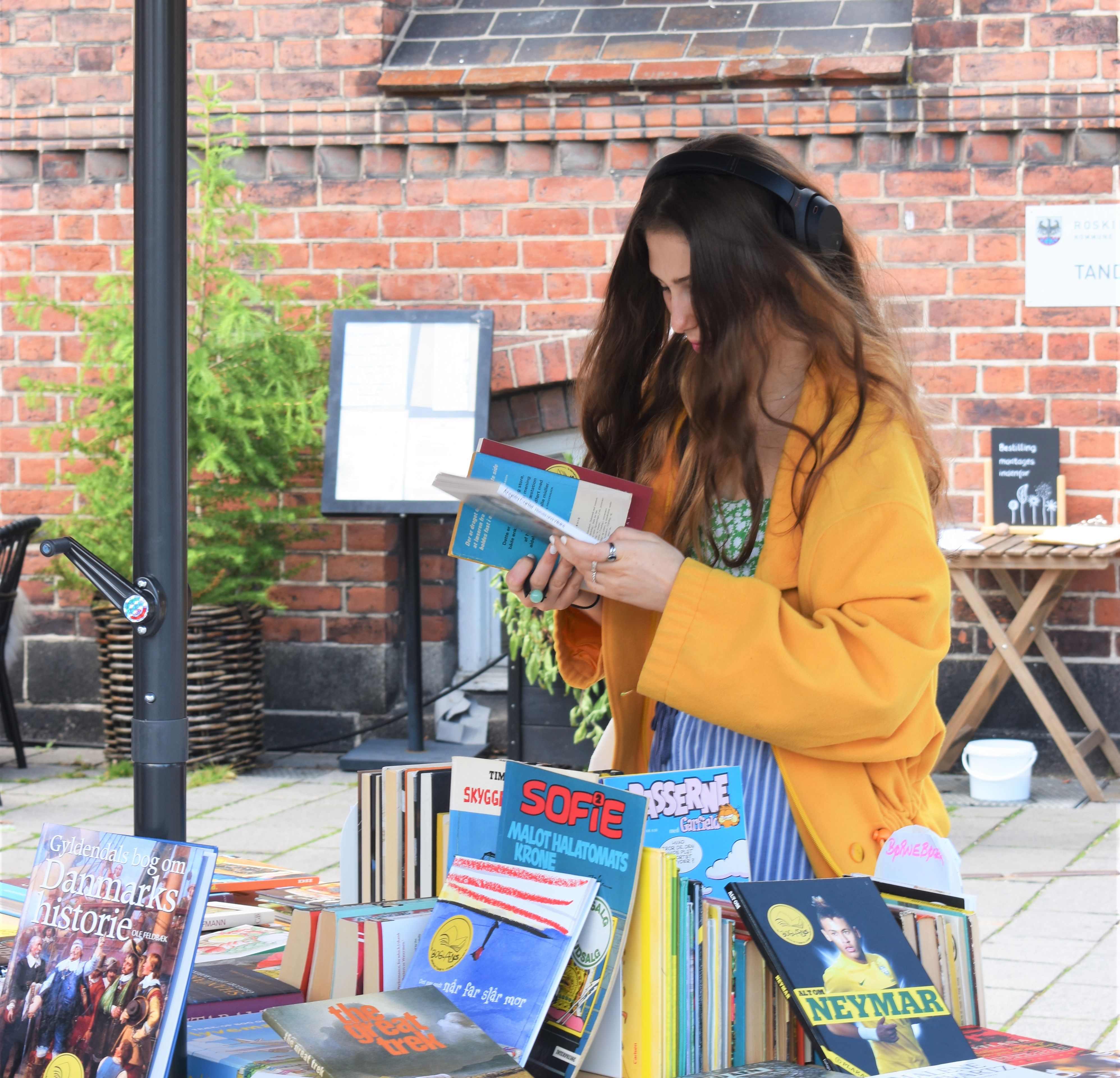 Kvinde i gul jakke kigger på bøger.