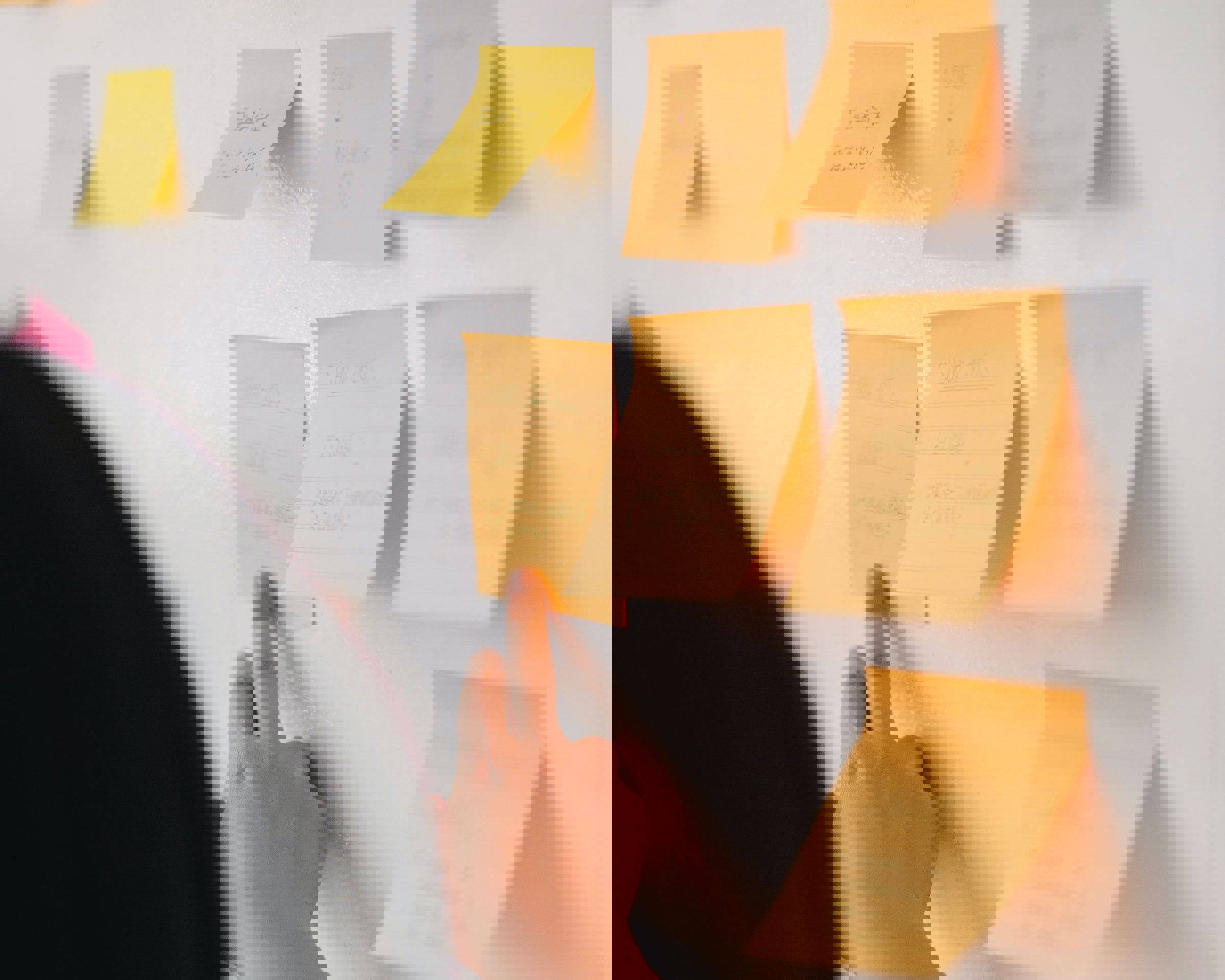 Person, der sætter en note på en væg. Der hænger flere noter på væggen.