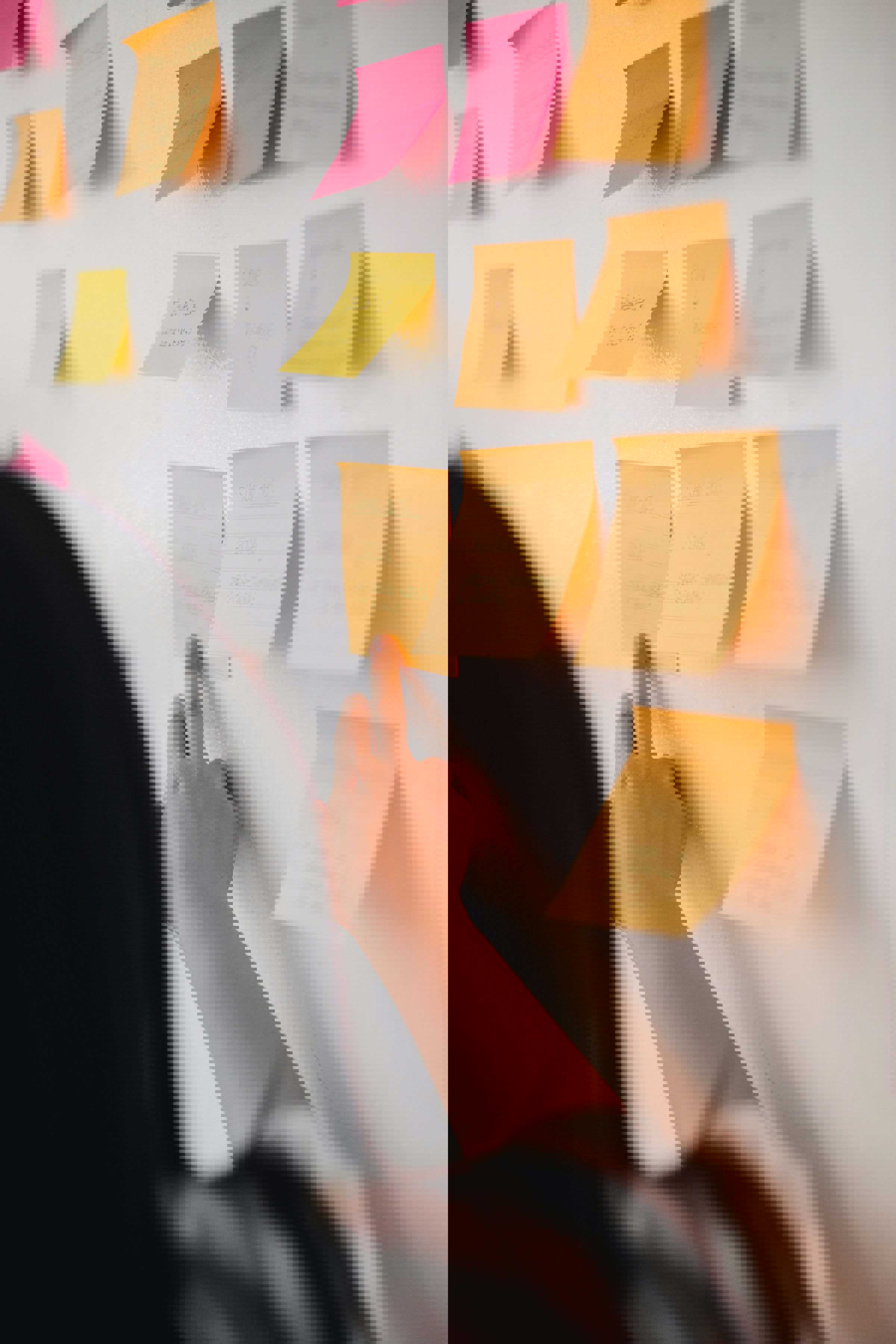 Person, der sætter en note på en væg. Der hænger flere noter på væggen.